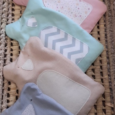 Cinco almofadas coloridas em forma de animal numa cesta de vime trançado