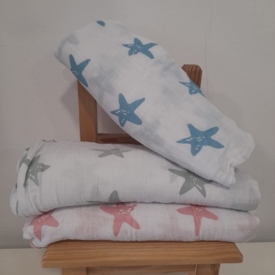 Mantinhas com padrão de estrelas do mar em três cores empilhadas numa cadeira de madeira