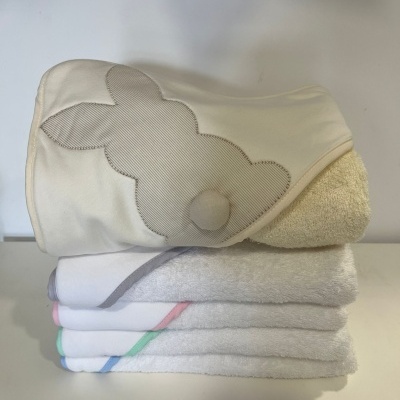 Toalhas de bebé brancas com bordas coloridas e toalha creme bordada com coelho cinzento.
