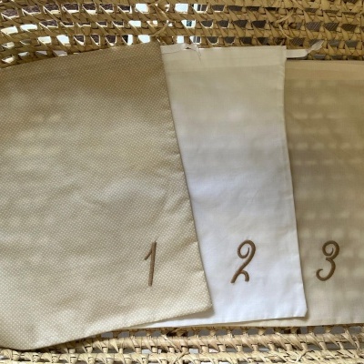 Três saquinhos de tecido numerados em cesta de vime