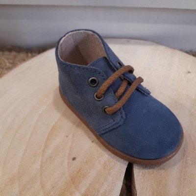 Sapato infantil azul em camurça com atacadores castanhos sobre madeira clara