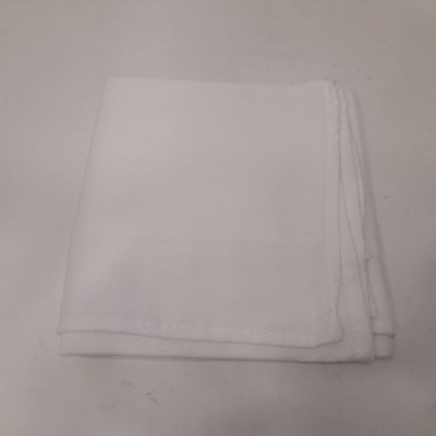 Guardanapo branco de tecido dobrado sobre superfície cinzenta