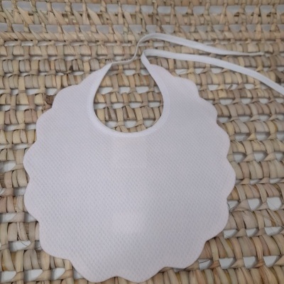 Babete branco com bordas onduladas sobre tapete de fibras naturais