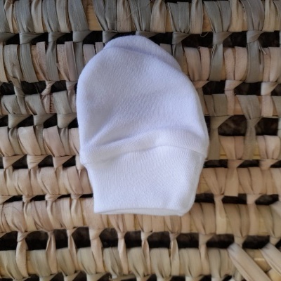 Meia branca para bebé sobre fundo de palha trançada