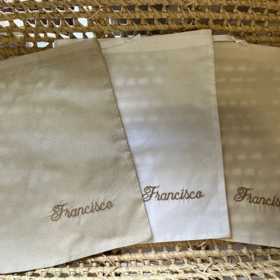 Três toalhas bordadas com o nome Francisco sobre superfície de vime