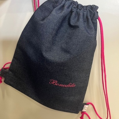 Mochila saco escura com cordões rosa e texto bordado 'Benedita'