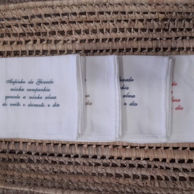 Cinco panos de cozinha brancos bordados em cesta de tecido trançado bege