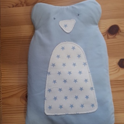Bolsa de água quente azul clara em forma de urso com estrelas azuis sobre fundo de madeira