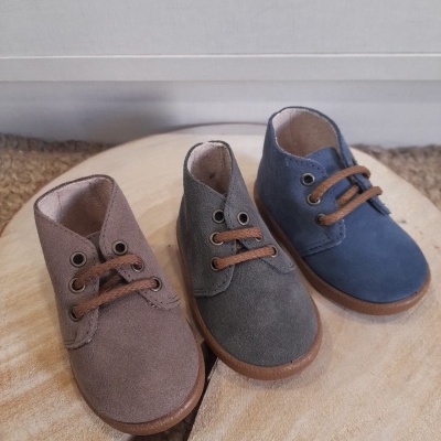 Três pares de botins infantis em camurça castanho, cinza e azul com atacadores castanhos