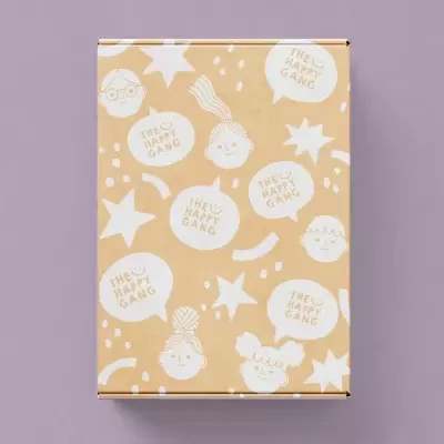 Caixa de cartão mel com rostos desenhados e texto THE U HAPPY GANG