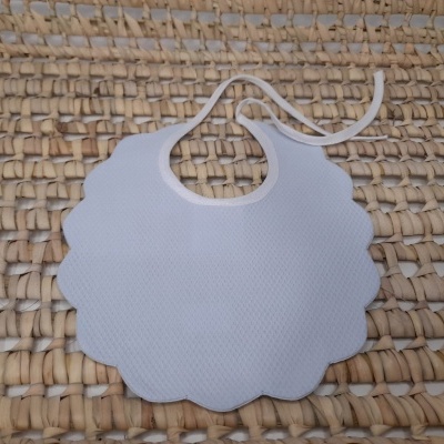 Babete branco com formato ondulado sobre superfície tecida