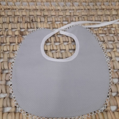 Babete claro com renda branca sobre superfície de entrelaçado natural