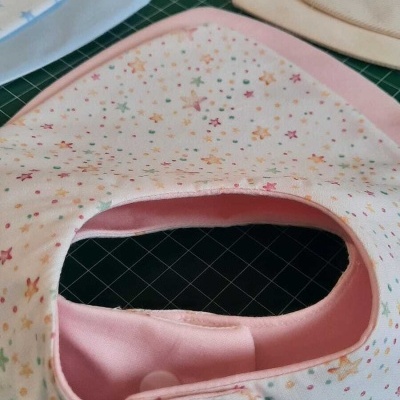 Babetes para bebé em vários tecidos e padrões sobre uma superfície verde escura