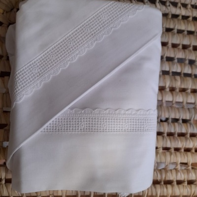 Toalha ou lençol branco com bordado sobre superfície trançada