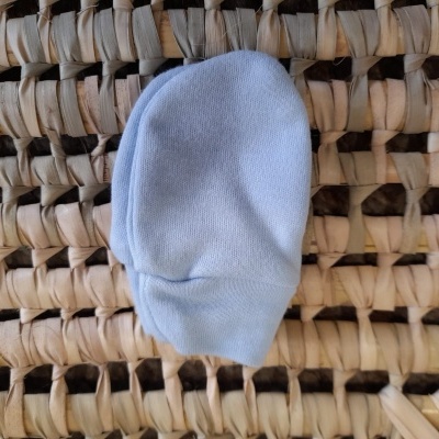 Luvas pequenas brancas sobre superfície entrelaçada de palha ou rattan