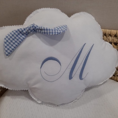 Almofada branca em forma de nuvem com laço às quadrículas azuis e letras bordadas 'M'