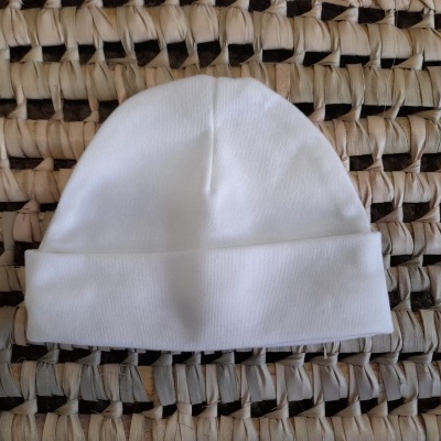 Gorro branco de bebé sobre superfície trançada