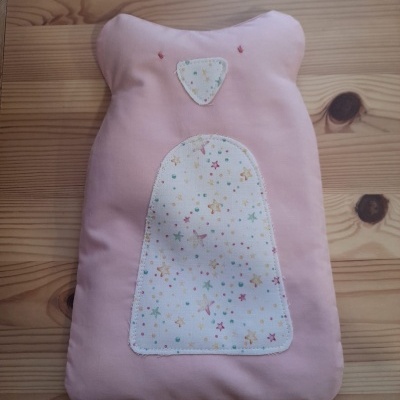 Almofada rosa formato urso com tecido estampado de estrelas em madeira clara