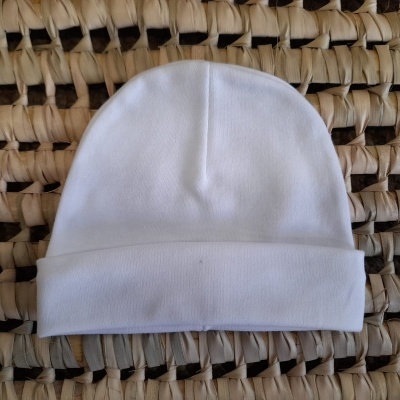 Gorro branco de tecido macio sobre superfície trançada bege e castanho