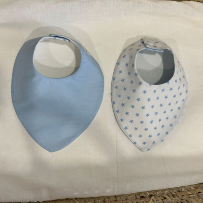 Dois babetes para bebé, um azul e outro branco com estrelas azuis