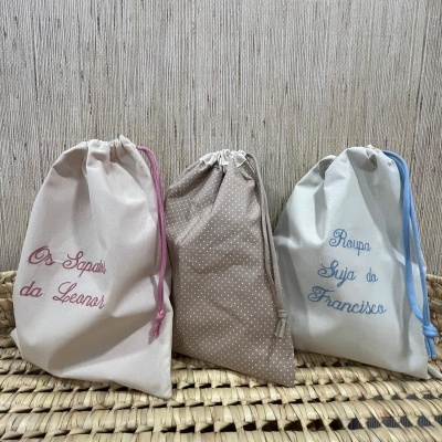 Três sacos de tecido com textos bordados e padrão de bolinhas