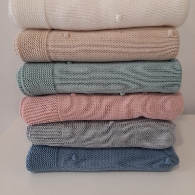 Pilhas de mantas de malha em tons pastel com textura
