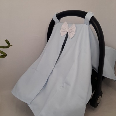Capa azul clara com laço branco numa cadeira de bebé preta