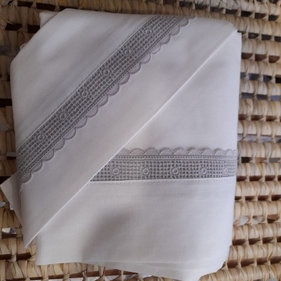 Lençóis brancos com renda cinza clara em superfície de material natural tecido