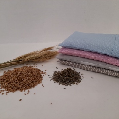 Três almofadas coloridas, sementes e ramos secos em fundo branco.