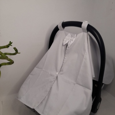 Capa protetora branca para cadeira de bebé com laço, em ambiente minimalista.