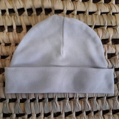 Gorro branco em tecido macio sobre superfície trançada natural