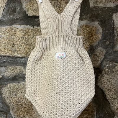 Macacão de malha bege para bebé pendurado numa corda com pregadeiras brancas