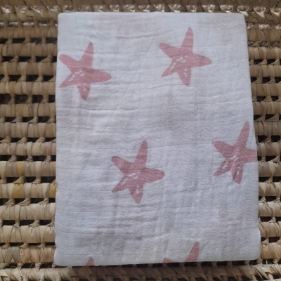 tecido branco com estrelas do mar cor de rosa sobre superfície de palha entrelaçada