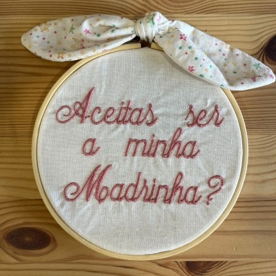 Aro de bordado em tecido branco com mensagem bordada em rosa e laço decorativo colorido