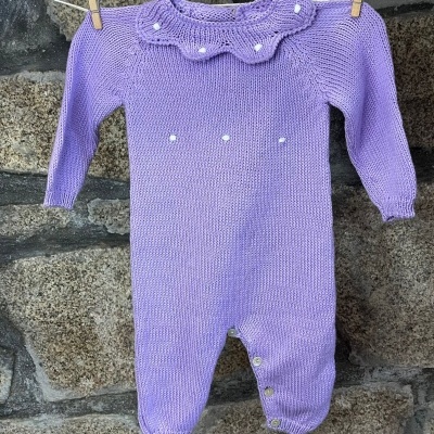 Macacão de bebé lilás em malha com gola ondulada e pérolas, pendurado num estendal