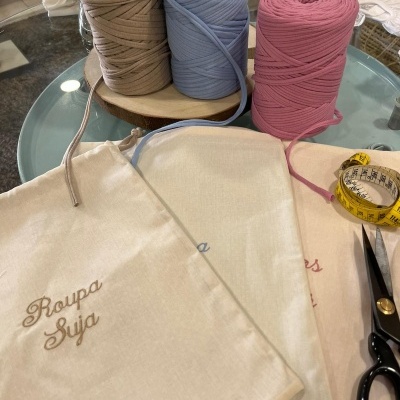 Rolos de corda de algodão e sacos de pano bordados sobre mesa de vidro