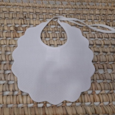 Babete branco de tecido com formato ondulado em superfície de palha entrelaçada