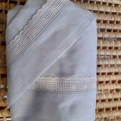 Lençol branco com bordado decorativo em renda em superfície trançada de palha