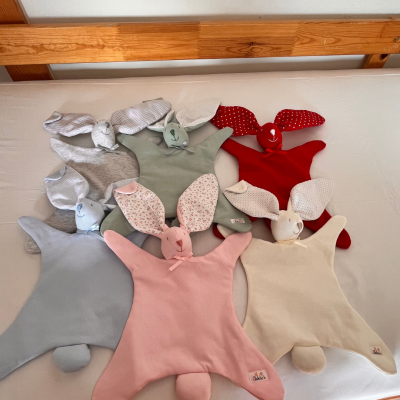 Bonecos de pano em forma de coelho coloridos sobre cama branca