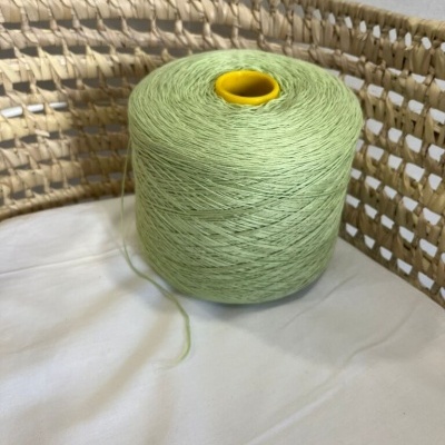 Cone de linha verde claro com tubo amarelo em cesto trançado