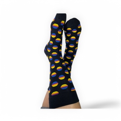 Meias pretas com bolas coloridas em pernas cruzadas