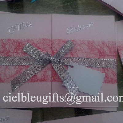 Convite em papel rosa com fitas prateadas e vermelhas e etiqueta branca suspensa