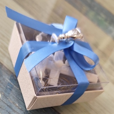 Caixa pequena com cruzes brancas e fita azul com sino prateado