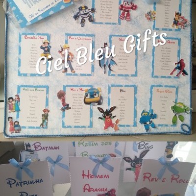 Quadro de festa infantil com listas de nomes e personagens animados, decoração azul e branca, pequenas placas com nomes e desenhos.
