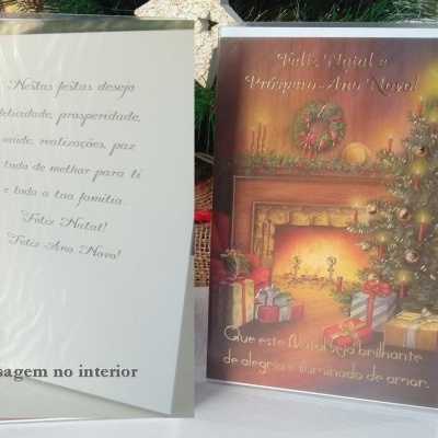 Dois cartões de Natal, um com capa colorida com lareira e presentes, outro aberto com mensagem em português.