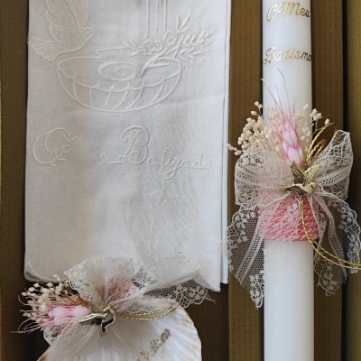 Conjunto de batismo com vela branca, toalha bordada e concha decorada em caixa castanha.