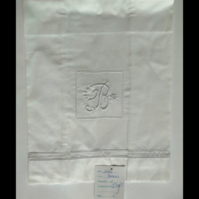 Toalha branca com bordado da letra B e etiqueta manuscrita