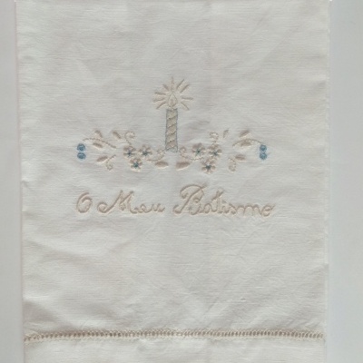 toalha branca com bordado de vela e texto O Meu Batismo