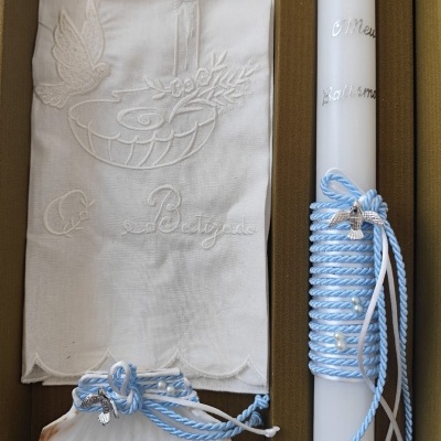 Conjunto de batismo com vela branca, toalha bordada e concha decorativa em azul e branco.