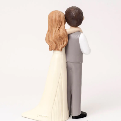 Figura decorativa de casal de costas, mulher com vestido branco e homem com colete cinza.